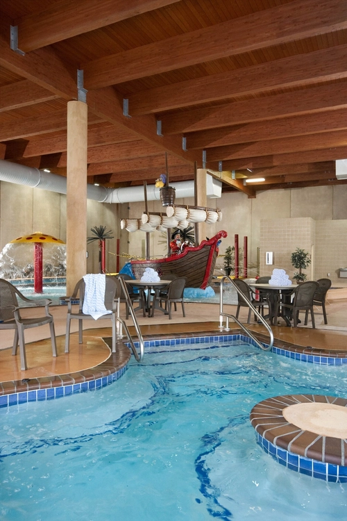 A indoor pool with a boat and chairs.